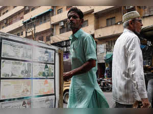 People walk past a sidewalk money exchange showcase, which is decorated with pictures of currency notes, in Karachi