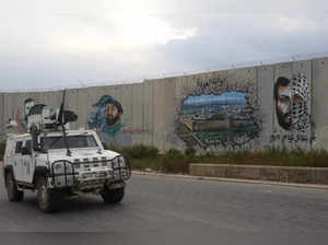 Peacekeepers of the United Nations Interim Force in Lebanon (UNIFIL) patrol near the border wall with Israel, painted with the portrait of slain Hezbollah commander Imad Moghnieh, in Lebanon's southern town of Kfar Kila on October 9, 2023.