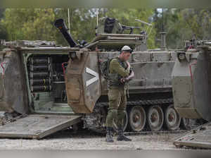 An Israeli soldier prays next to an APC at a staging ground near the Israeli Gaz...