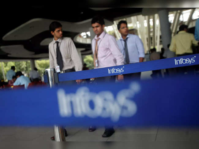 FILE PHOTO: Employees of Indian software company Infosys walk past Infosys logos at their campus in the Electronic City area in Bangalore