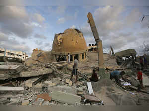 People stand outside a mosque destroyed in an Israeli air strike in Khan Younis,...