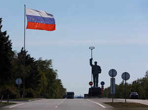 A Russian flag flies near a monument to a steelworker in Mariupol