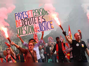 Protestors wave smoke canisters during a demonstration as part of a nationwide day of strike called by France's inter-unions representatives to push wages hikes and to ask for equality between men and women in Paris on October 13, 2023.