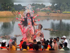 Hindu devotees prepare to immerse an idol of the Hindu Goddess Durga in a pond during the final day of the 'Durga Puja' festival in Andawa village, some 16 Km from Prayagraj on October 24, 2023.