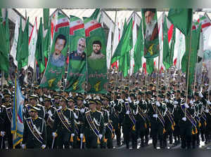 Iran's Revolutionary Guard members march as they carry flags with portraits of t...
