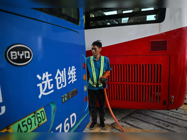 In this picture taken on October 18, 2023, a worker disconnects a charging cable from an electric bus at Antuoshan charging station in Shenzhen, China's southern Guangdong province.