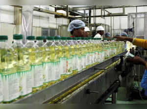 FILE PHOTO: Employees fill plastic bottles with edible oil at an oil refinery plant of Adani Wilmar Ltd in Mundra