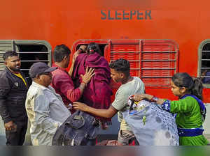 Surat: Passengers try to board a train through a window at a platform on the eve...