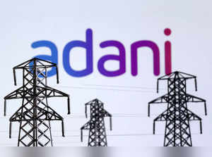 FILE PHOTO: Illustration shows Electric power transmission pylon miniatures and Adani Green Energy logo