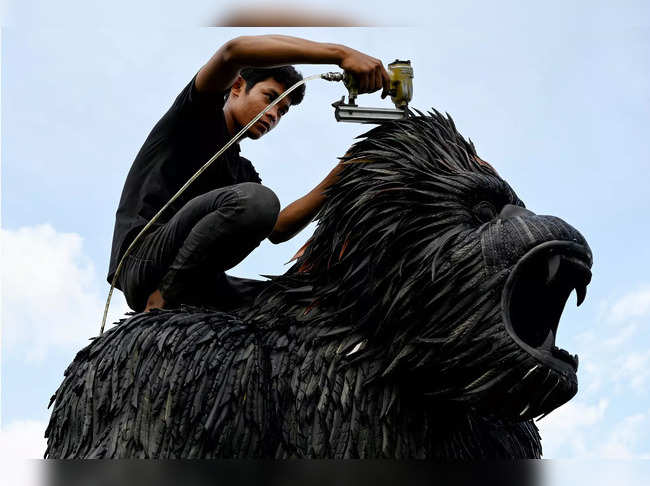 This photo taken on November 7, 2023 shows a worker fixing a King Kong statue made with old motorbike and bicycle tyres at artist Mean Tithpheap's house in Kandal province.