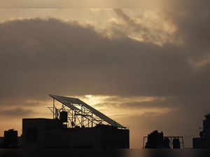 The sun rises behind a solar panel array installed atop a rooftop in Rafah in the southern Gaza Strip on November 9, 2023.