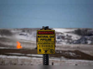 FILE PHOTO: A warning sign for a natural gas pipeline is seen as natural gas flares at an oil pump site outside of Williston