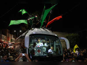 A bus transporting Red Cross staff and Palestinians prisoners released from Israeli jails in exchange for hostages released by Hamas from the Gaza Strip, drives through supporters holding flags in Ramallah in the occupied West Bank early on November 26, 2023.