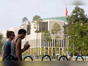 Tourists walk past Vietnam's National Assembly