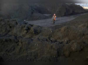 FILE PHOTO: Worker walks past coal piles at a coal coking plant in Yuncheng