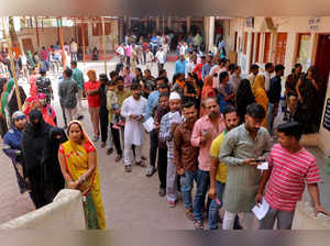 People wait in queues to cast their votes at a polling station in Indore