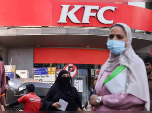 People walk past a sotre of the Kentucky Fried Chicken (KFC) fast food restaurant chain in Mumbai