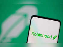 Robinhood logo is seen on a smartphone in front of a displayed logo in this illustration
