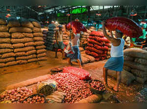 Kolkata: Workers sort onions at a godown of a wholesale market as onion prices s...