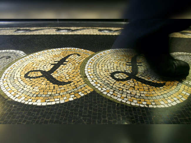 FILE PHOTO: File photograph shows an employee walking over a mosaic depicting pound sterling symbols on the floor of the front hall of the Bank of England in London
