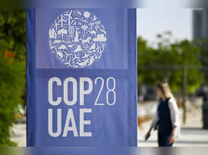 A woman walks past a COP28 logo ahead of the United Nations climate summit in Dubai on November 28, 2023.