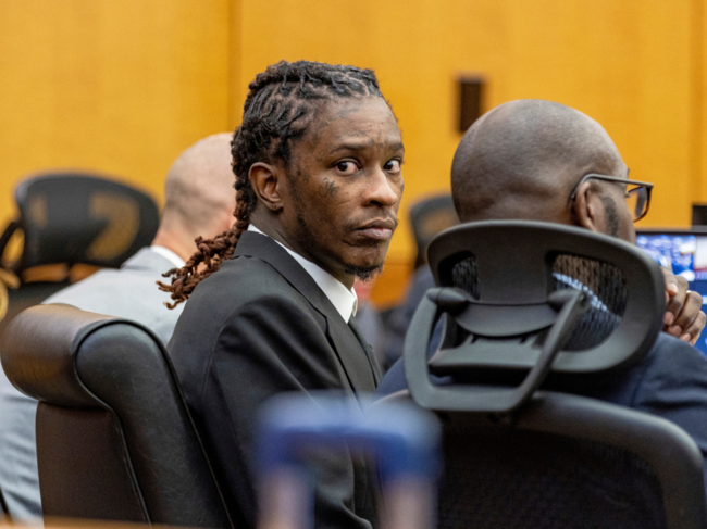 The trial of rapper Young Thug and five co-defendants has been delayed after one of them was stabbed in the Fulton County Jail in Atlanta.