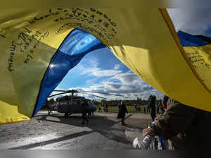 Onlookers with an Ukrainian flag stand next to a Black Hawk helicopter at Letna Park during the presentation of the "Gift for Putin" project in Prague, Czech Republic on November 17, 2023.