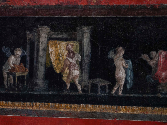 Busy winged cupids dyeing textiles are painted on a frieze at waist level that runs around the living room in one of the wealthiest homes in Pompeii.