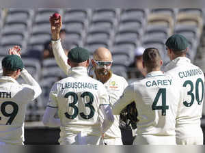 Australia's Nathan Lyon, center, holds the ball aloft after dismissing Pakistan'...