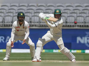 Australia’s Usman Khawaja (R) plays a shot as Pakistan's  Agha Salman looks on on day four of the first Test cricket match between Australia and Pakistan in Perth on December 17, 2023.