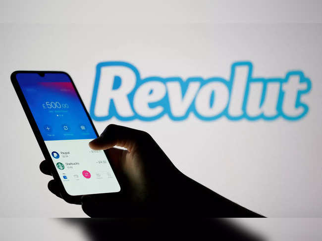 FILE PHOTO: Woman holds smartphone with Revolut app in front of displayed Revolut logo in this illustration