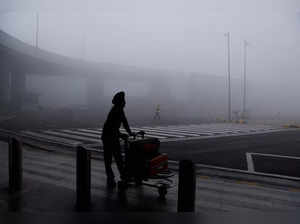 A man is seen with his luggage cart amidst heavy fog at the Indira Gandhi International Airport in New Delhi