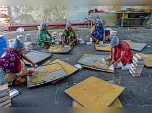Workers pack freshly prepared Chikki, a traditional Indian sweet made with sesame seeds, nuts and jaggery, at a workshop in Rakanpur village, on the outskirts of Ahmedabad on December 23, 2023.