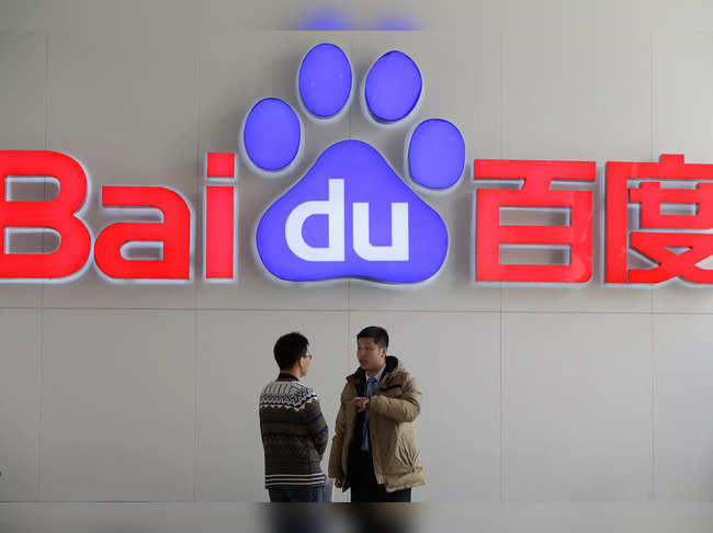 FILE PHOTO: People talk in front of a Baidu's company logo at Baidu's headquarters in Beijing