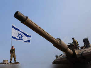 An Israeli soldier waves an Israeli flag on a tank, near the Israel-Gaza border
