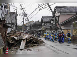 Police walk past collapsed houses hit by earthquakes in Suzu, Ishikawa prefectur...