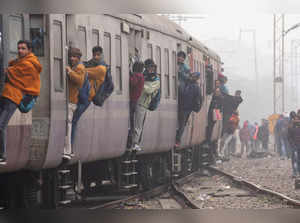 New Delhi: Passengers hang out from a train as it approaches a station during a ...