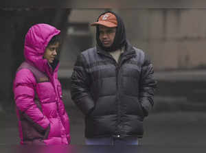 New Delhi: People wearing warm clothes wait at a bus stop during a cold winter d...