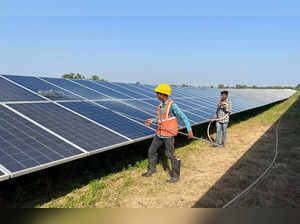 FILE PHOTO: Workers clean panels at a solar park in Modhera