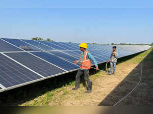 Workers clean panels at a solar park in Modhera