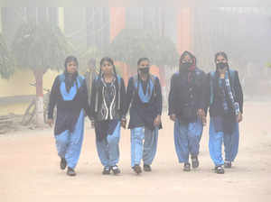Patna: Students arrive at a school during fog on a cold winter morning, in Patna...