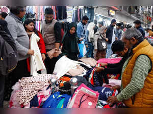 People purchase warmer clothes from a street vendor as temperature drops in Dhaka