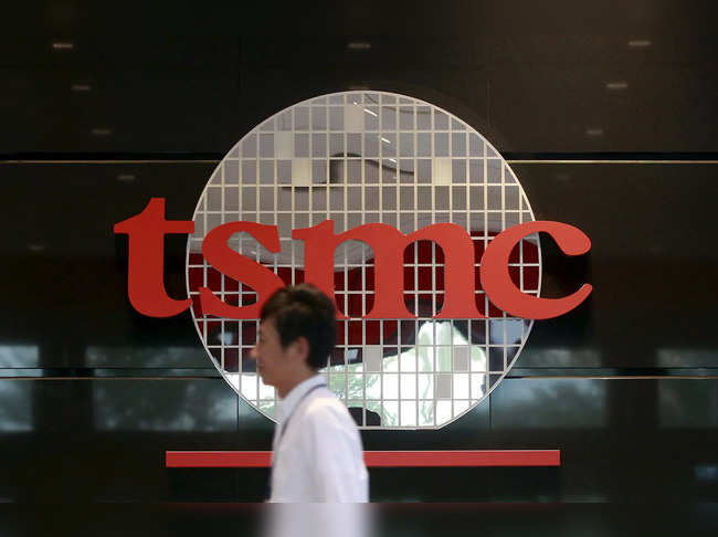 An employee walks in front of logo of Taiwan Semiconductor Manufacturing Co Ltd (TSMC) at its headquarters in Hsinchu