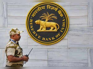 Mumbai: A security official walks past an emblem of the Reserve Bank of India (R...