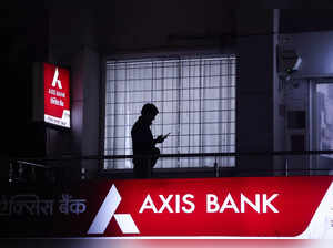 A person uses their mobile phone outside a branch of  Axis Bank in New Delhi