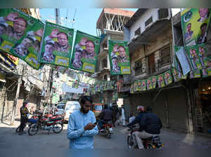 Commuters ride past posters of Nawaz Sharif Pakistan's former Prime Minister and leader of the Pakistan Muslim League (PML) party, a day after national elections in Lahore on February 9, 2024.