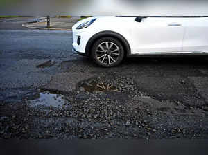 A car is driven past a pothole in a damaged road in Liverpool, north west England on January 30, 2024.