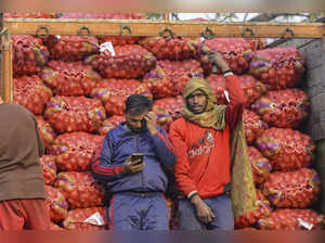 Jalandhar: Workers stand next to a truck loaded with sacks of onion at a wholesa...