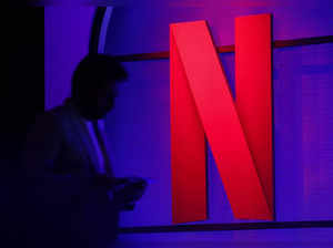 A man stands next to a logo of Netflix during an event in Mumbai