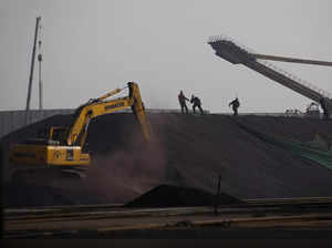 Labors work on a pile of iron ore at a steel factory in Tangshan in China's Hebei Province